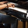 Adsilent system shown attached underneath acoustic piano keyboard with child playing the piano with headphones on